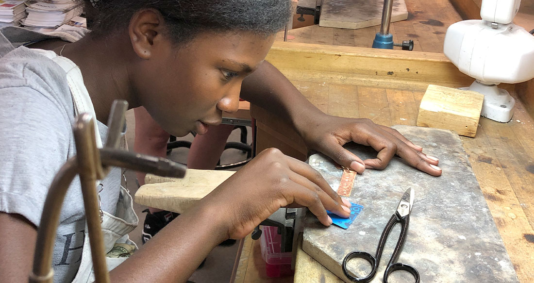 FIT precollege jewelry making class, student at a worktable 