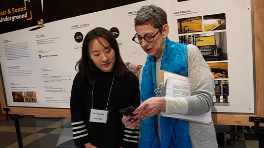 a student confers with a faculty member, look at an image on phone