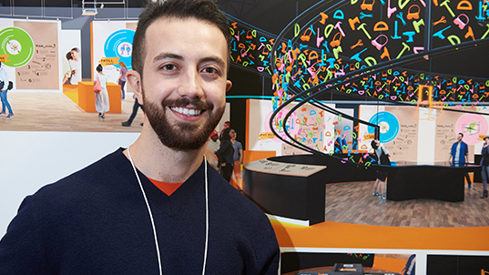 a student smiles in front of a display of project photos