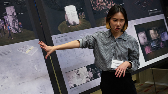 a student points at a rendering during a presentation