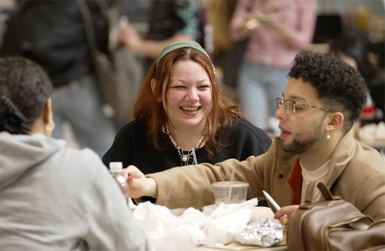still frame for the video showing group of laughing students sitting at a table in the dining hall