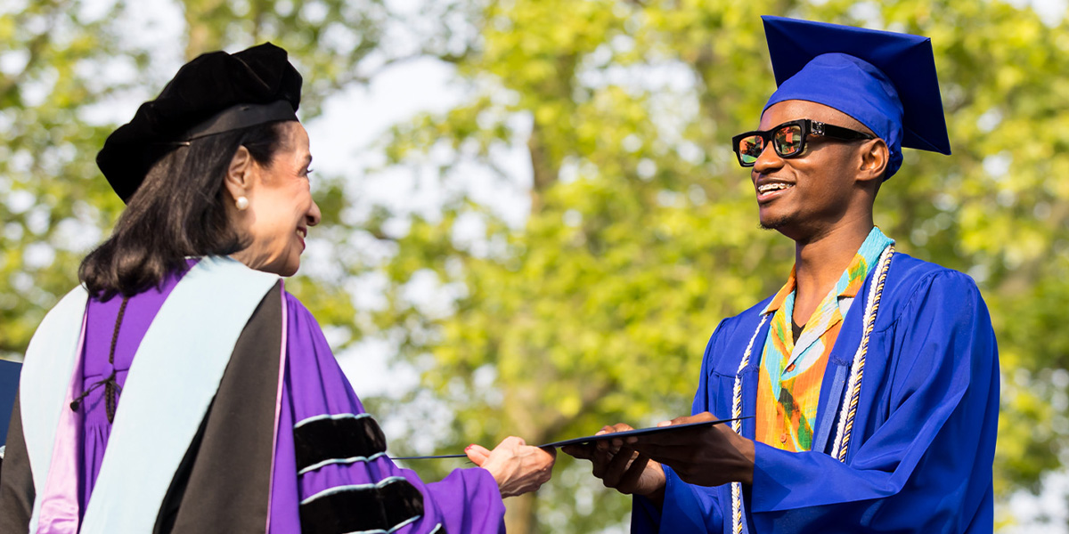 Joyce F. Brown hands diploma to graduate
