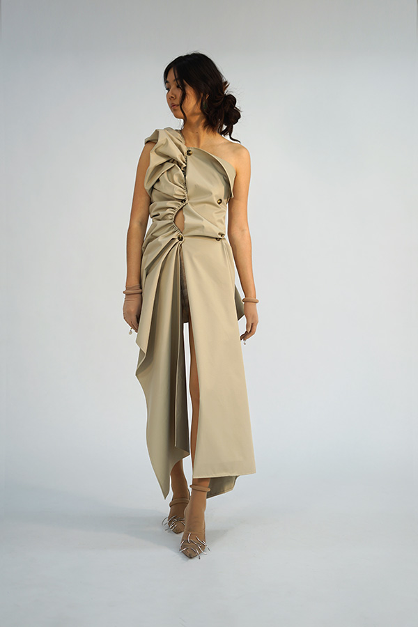 Model wearing a beige dress made to look like a deconstructed, ruched trench coat. 